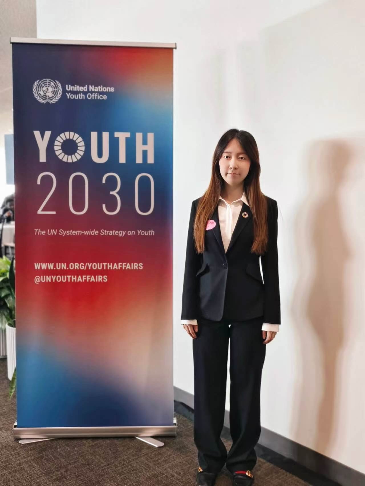 Qianhao Han beside the UN Youth Office Youth 2030 display
